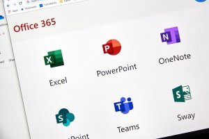 A computer screen displaying the Microsoft 365 app suite, including Excel, PowerPoint, OneNote, and Teams.
