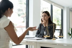 Two legal professionals discuss data security and risk reduction strategies at a desk with justice scales.