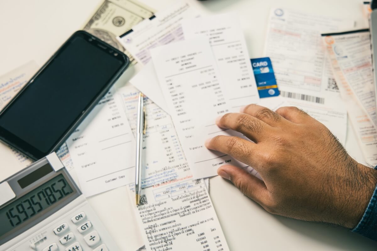 Law Firm Budget Planning A person reviews a desk scattered with invoices, a calculator, and a smartphone, symbolizing legal cybersecurity budgeting.