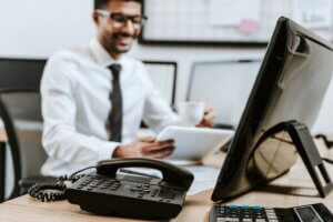 A professional works at a desk with a desktop computer and office phone, showing a modern legal IT environment.
