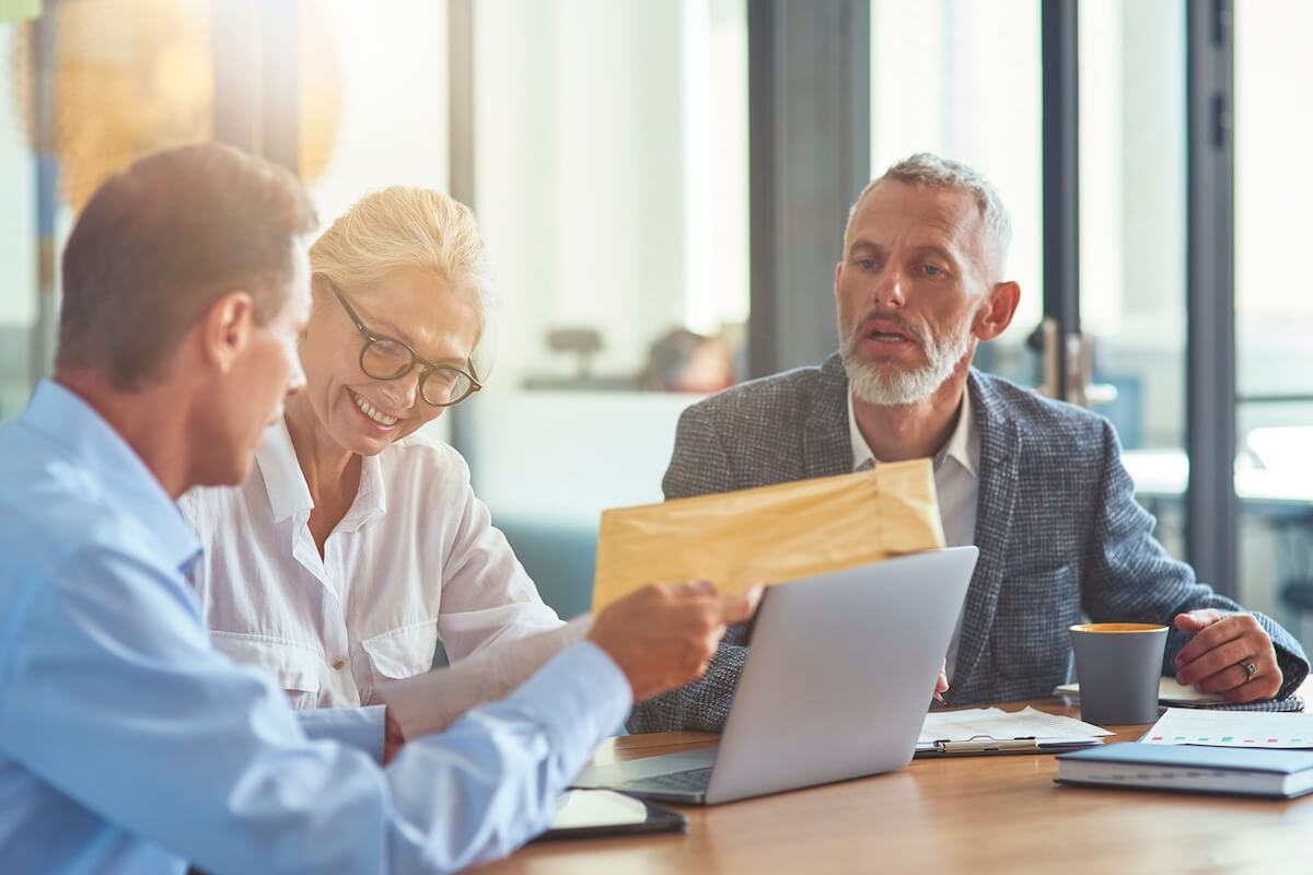insurance-agency-compliance-review-security-audit Business colleagues reviewing documents and laptop data together during a compliance meeting at a conference table.