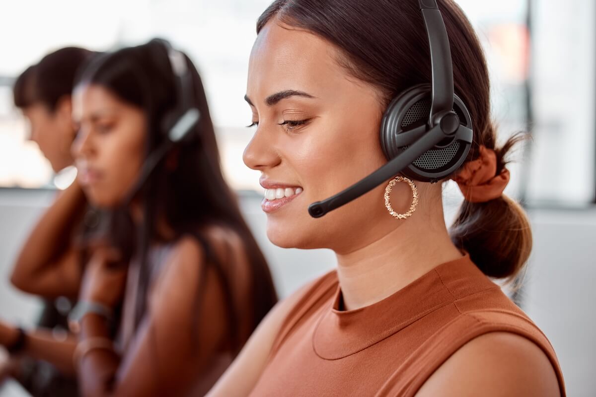 insurance-agency-it-provider-response-times Customer service agent wearing a headset smiling while providing fast support in a busy office setting.