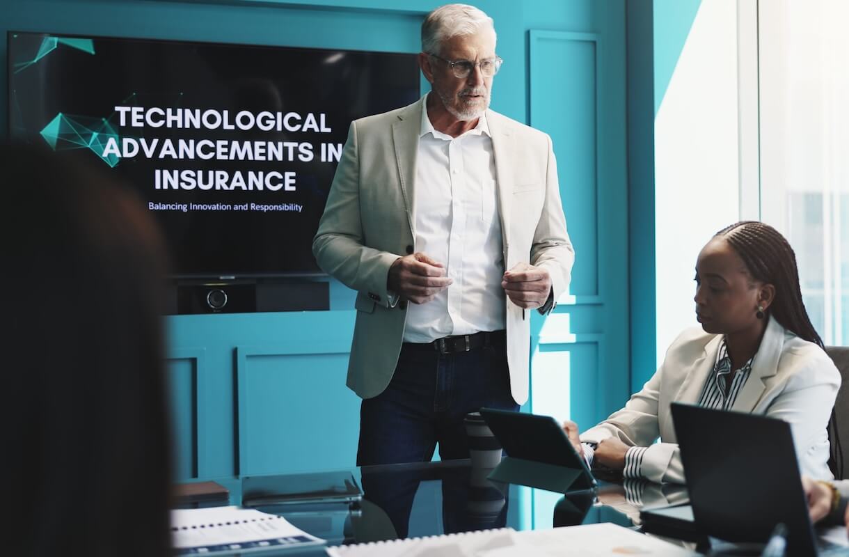 insurance-ransomware-disaster-recovery-prep Executive presenting tech strategy in front of a screen reading Technological Advancements in Insurance.