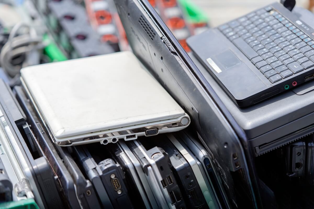 legacy-technology-risks Stack of outdated, old laptops stacked together representing hardware lifecycle and obsolete technology risks.