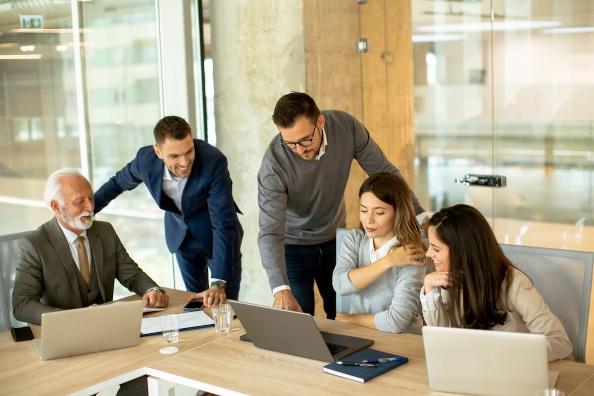 Team of professionals gathered around a laptop screen collaborating on modern technology strategy in a modern office.