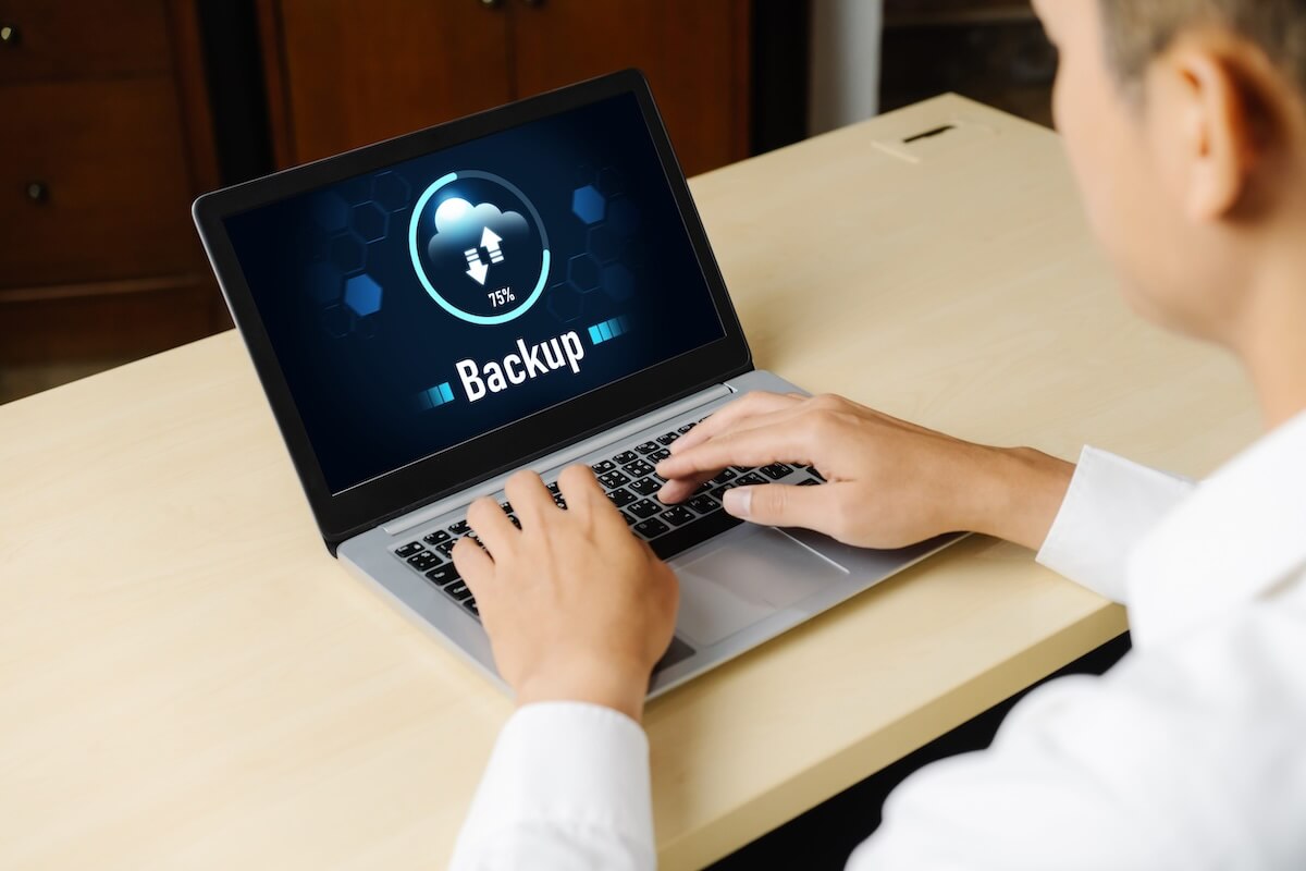 non-profit-backup-bcdr Employee using a laptop with a cloud data backup in progress