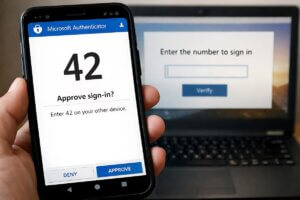 Microsoft authentication code on a smartphone beside a laptop
